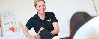 Therapeut führt Übung am Bein eines Patienten durch