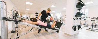 Trainer unterstüzt Patientin beim Stretching