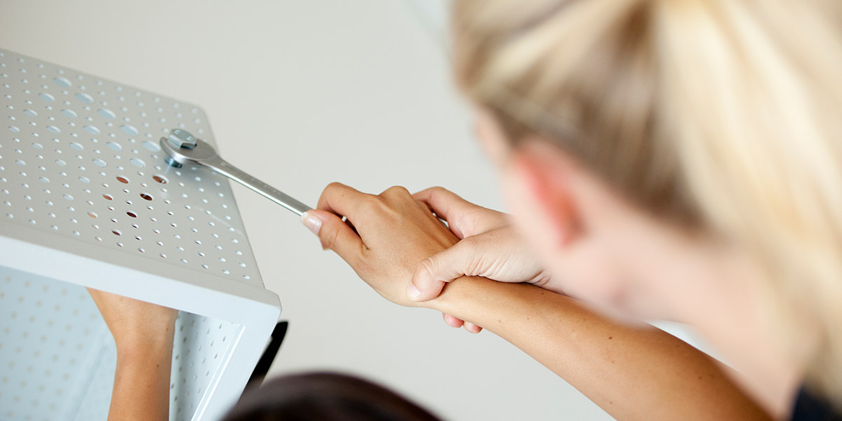Eine Person führt Handtherapie durch, indem sie die Hand einer anderen Person hält und unterstützt.