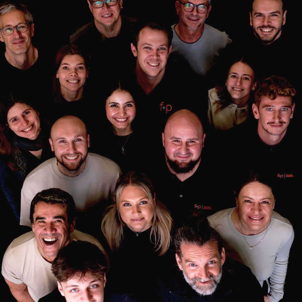 Gruppenfoto von Mitarbeitern des fp-Teams, die in einem engen Kreis stehen und in die Kamera lächeln.