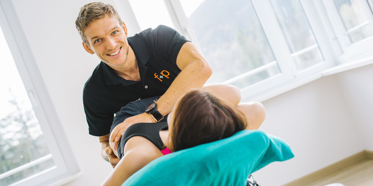 Physiotherapeut führt manuelle Therapie an einer Patientin in einer hellen Umgebung durch.