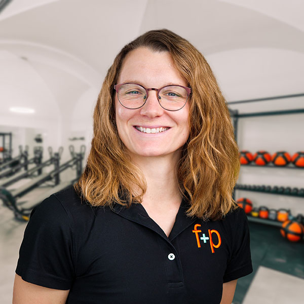 Nina Olschewski Eine Person mit Brille und lockigem Haar trägt ein schwarzes Sportshirt mit einem Logo.