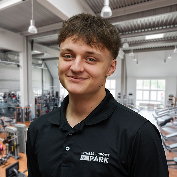 Junger Mann mit kurzem Haar in einem schwarzen Sporthemd in einem Fitnessstudio.