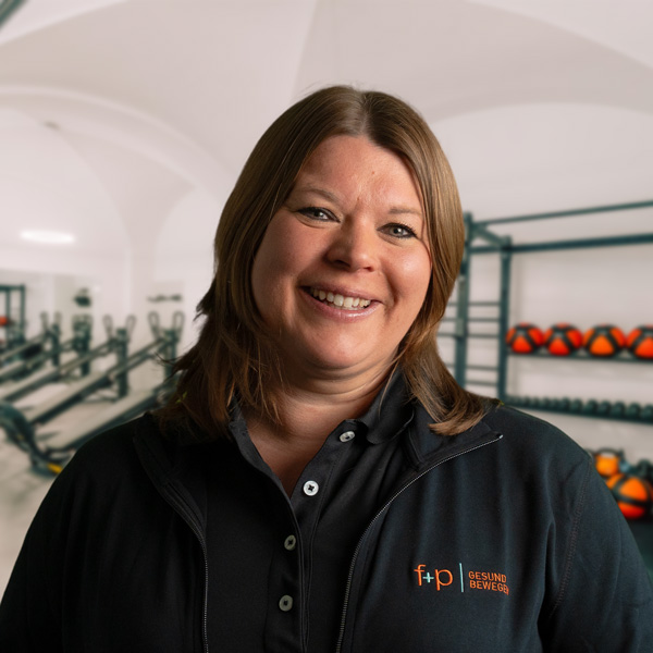 Yvonne Derks lächelt in einem Fitnessstudio mit Gewichten im Hintergrund.
