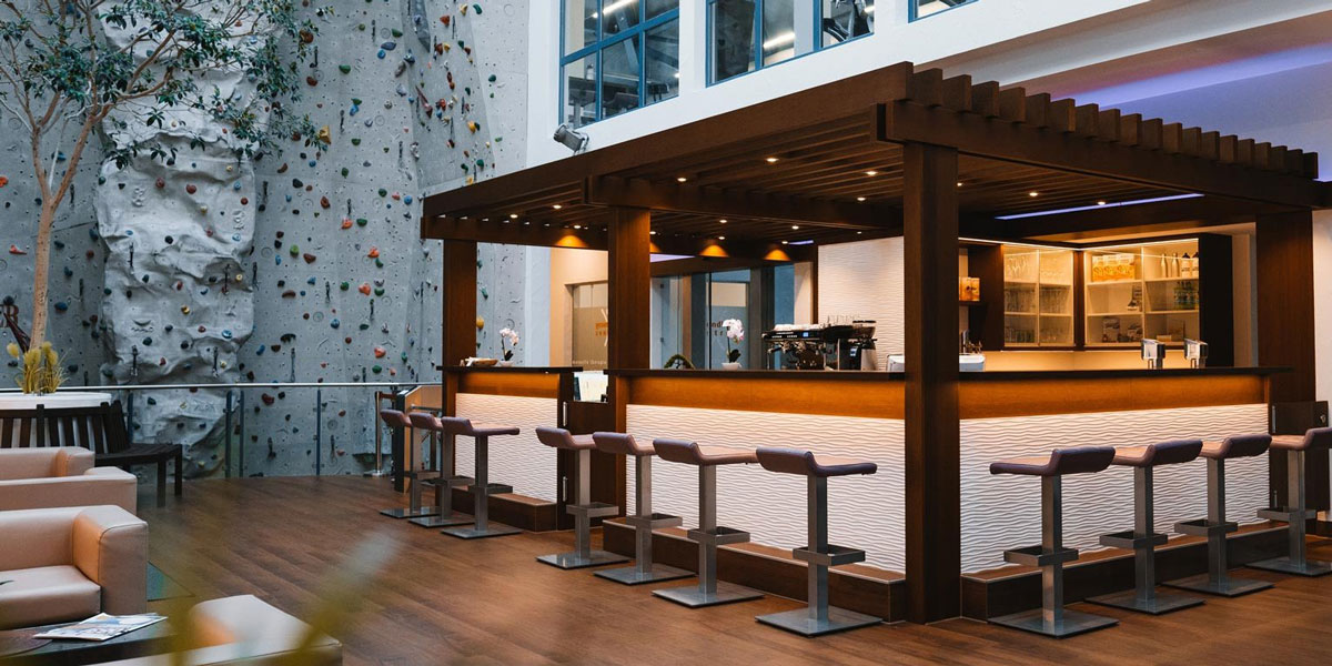 Moderne Café-Bar mit Holzstruktur, Sitzplätzen und beleuchtetem Tresen in einem Innenraum.