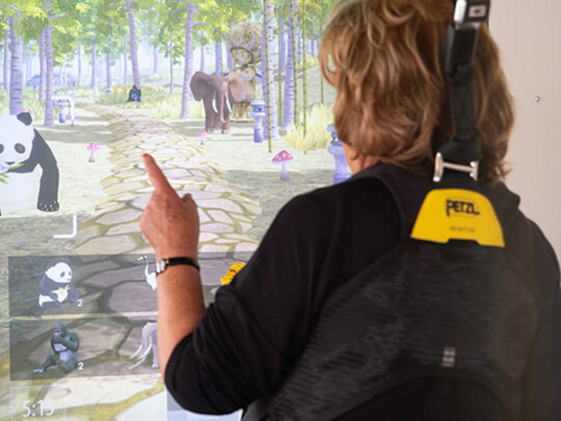 csm_c_mill_virtuell_a4c757ca34 Eine Person zeigt auf einen virtuellen Bildschirm mit Tieren und einem Waldweg.