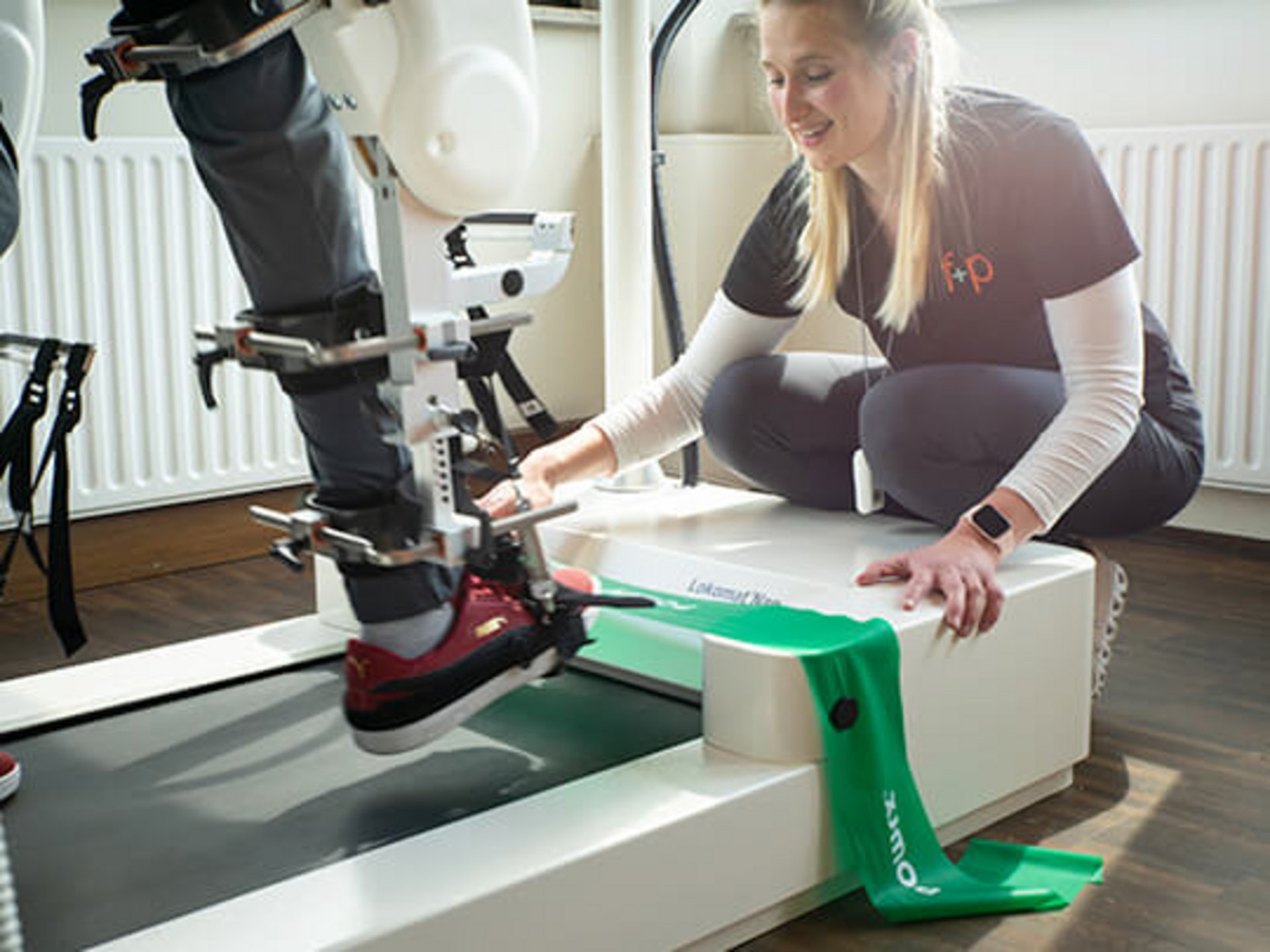 Physiotherapeutin arbeitet mit einem Patienten, der ein Lokomat-Gangtherapiegerät nutzt.