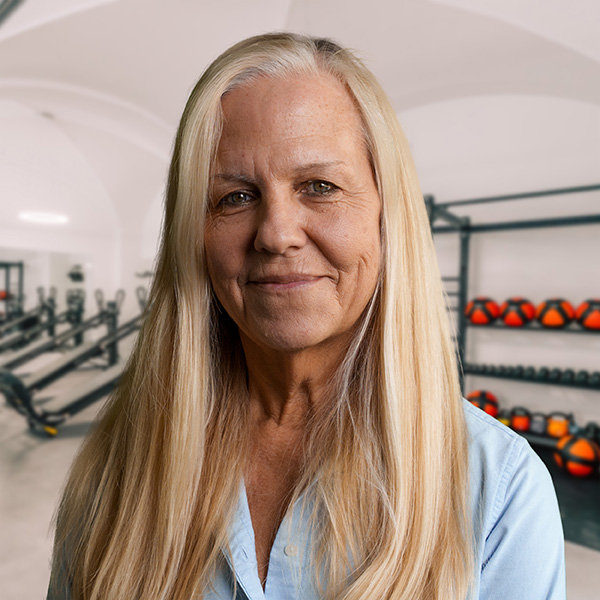 IlonaBa Eine Frau mit langen blonden Haaren und einem freundlichen Gesichtsausdruck in einem Fitnessstudio.