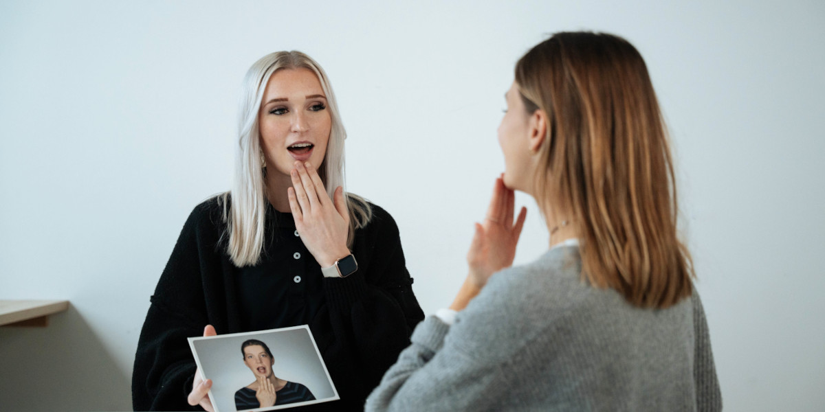 Zwei Frauen, eine zeigt auf ein Bild und spricht, während die andere auf sich selbst zeigt.