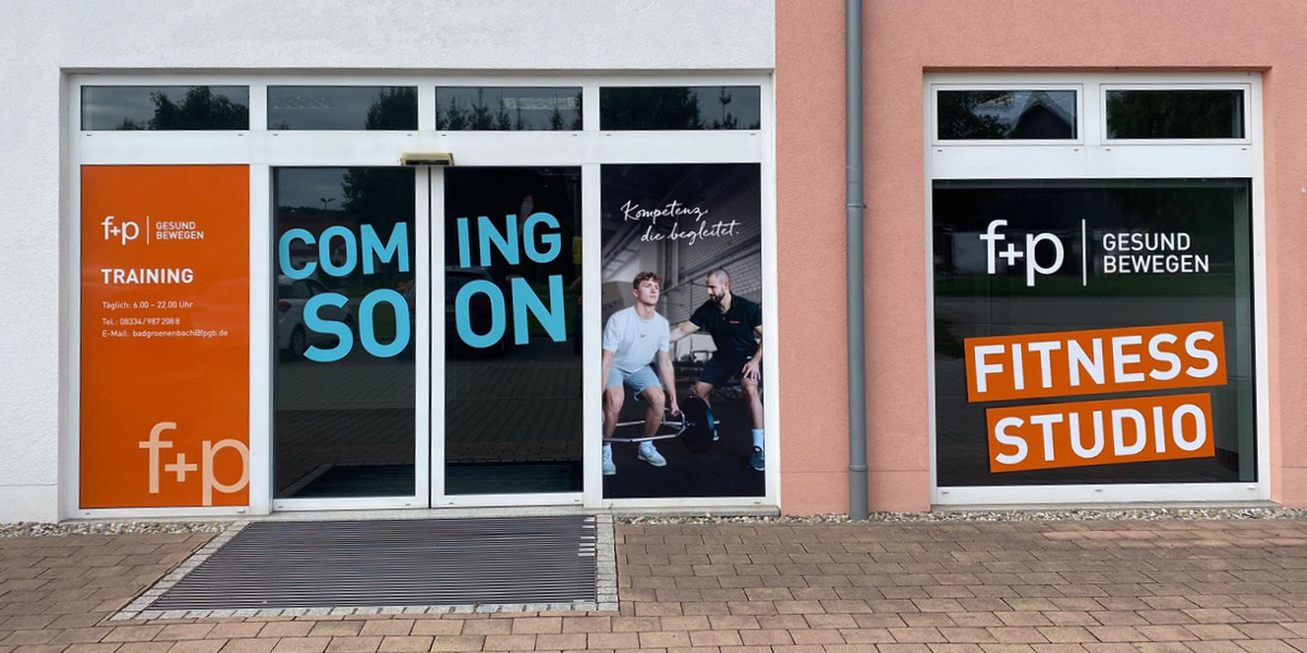 Eingang des Fitnessstudios f+p Gesund Bewegen mit Werbeflächen und Fenstergestaltung.