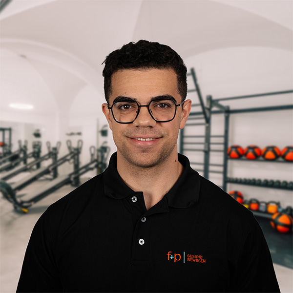 NoahMa Mann mit Brille und schwarzem Poloshirt steht in einem Fitnessstudio mit Trainingsgeräten im Hintergrund.