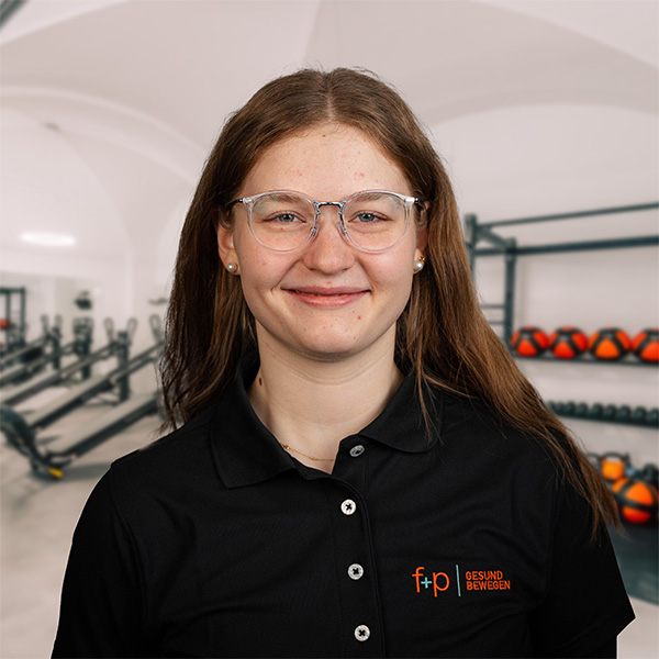 Junge Frau mit Brille trägt ein schwarzes Polohemd mit dem Logo von f+p Gesund Bewegen.