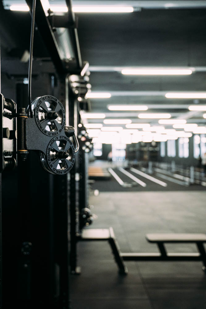 Schwarze Gewichtsscheiben an einem Fitnessgerät in einem modernen Fitnessstudio mit hellen Deckenleuchten.