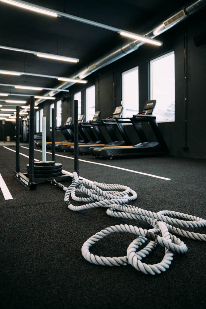 Trainingsgeräte in einem Fitnessstudio mit Seil und Schlitten auf dem Boden.