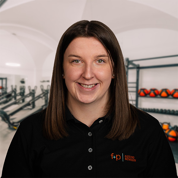 LeSchle Frau mit langen Haaren in einem schwarzen Poloshirt mit dem Logo von f+p Gesund Bewegen.