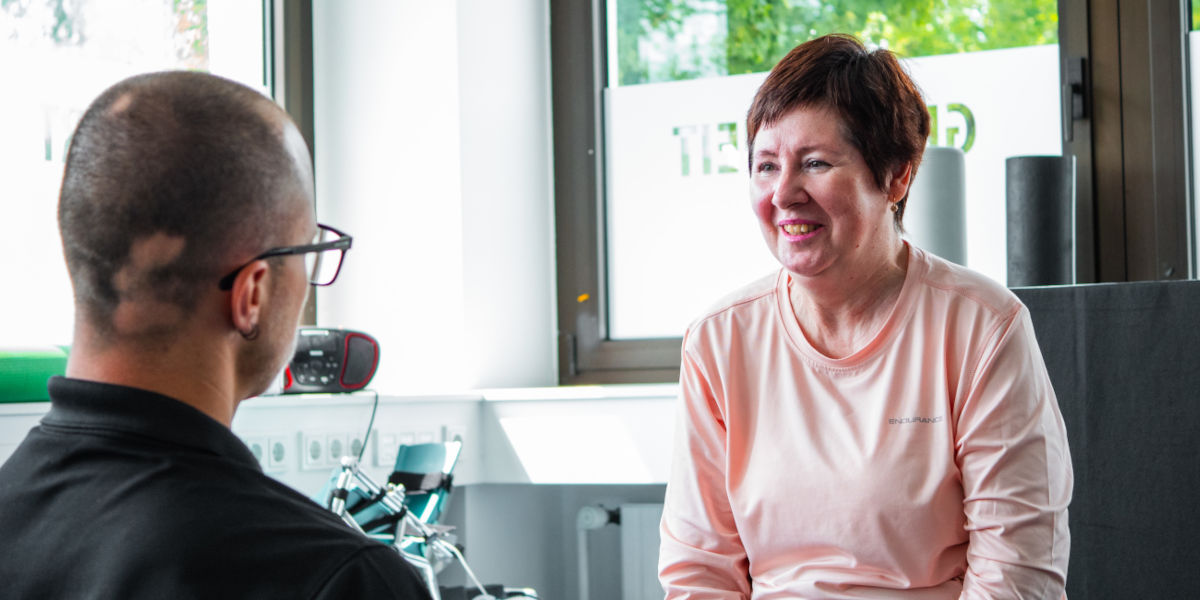 Eine Patientin lächelt während einer Beratung mit einem Fachmann in einer modernen Praxis.