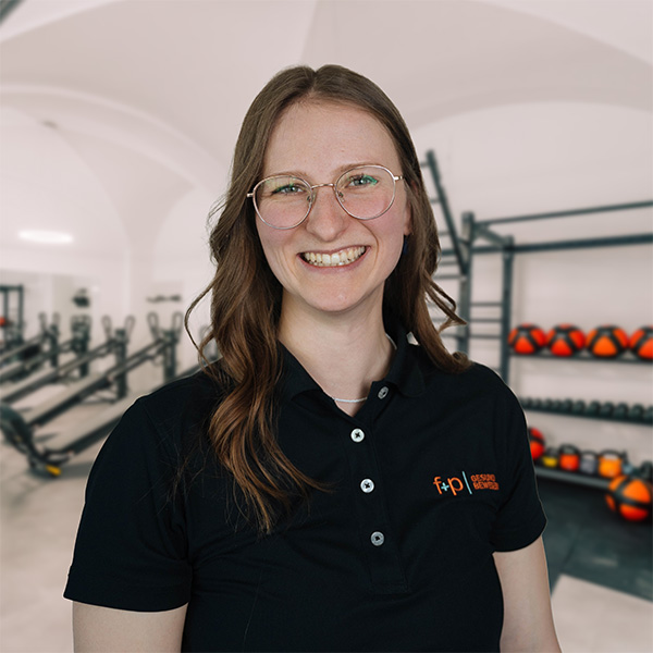 SiGr Mit freundlichem Lächeln: Silvia von f+p Gesund Bewegen im schwarzen Polo mit Brille in der Praxisumgebung im Allgäu.