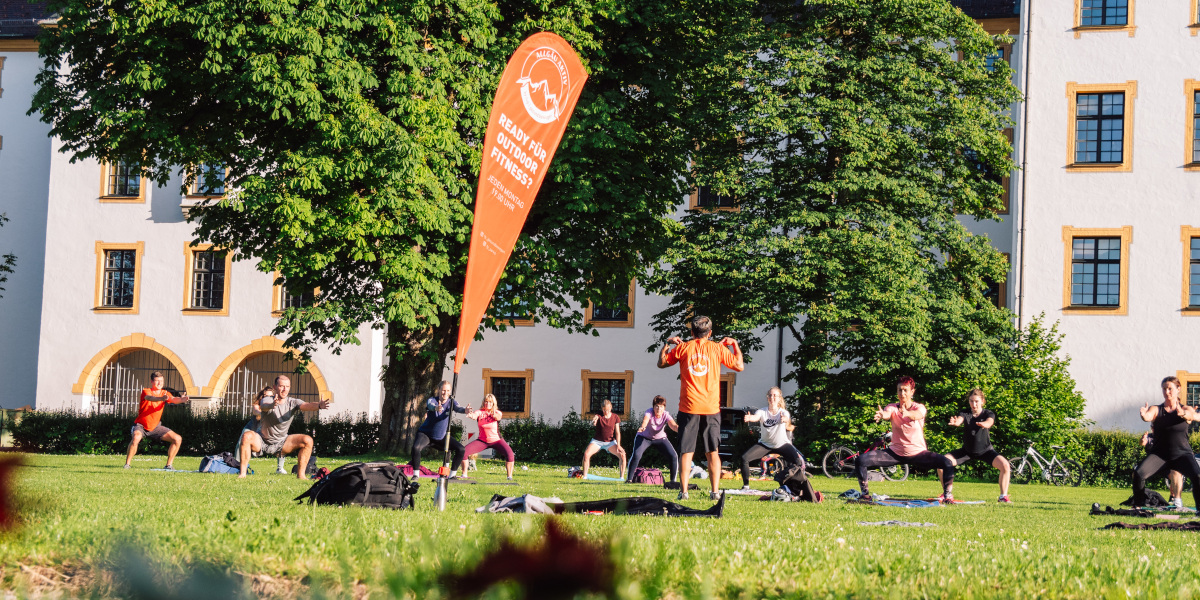 Beim kostenlosen Outdoor-Training von f+p Fitness im Allgäu Aktiv trainieren Teilnehmende im Kemptener Hofgarten gemeinsam im Grünen.